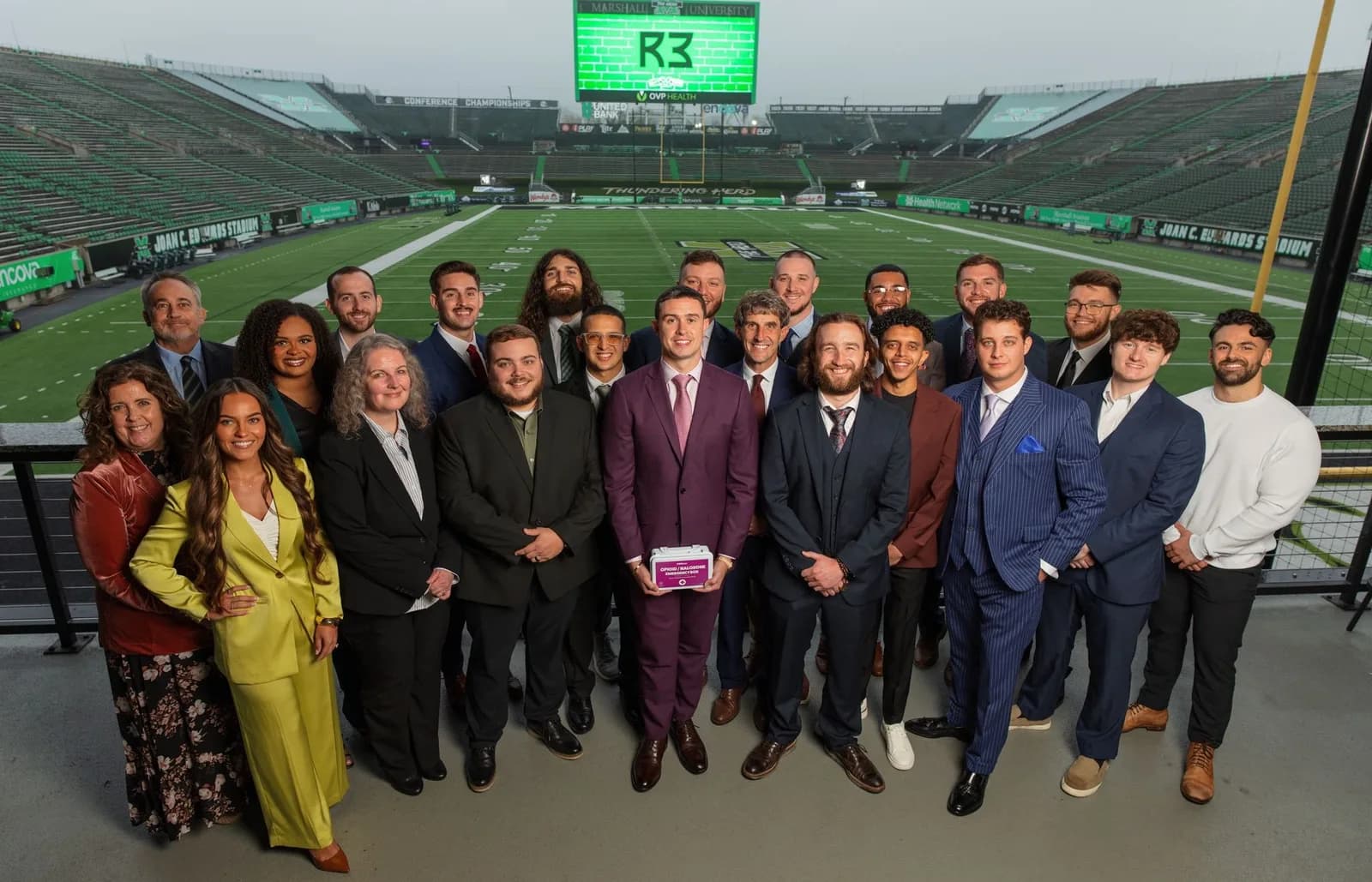 The R3 team gathered at Joan C. Edwards Stadium with the R3 logo on the jumbotron